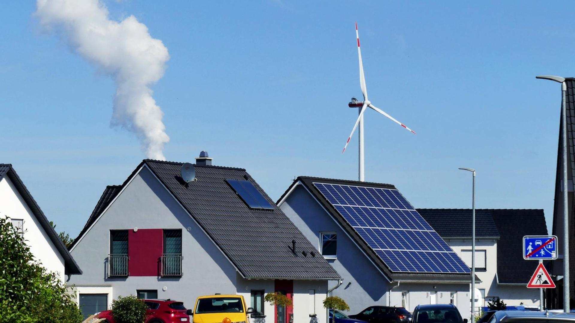 Neubaugebiet in Elsdorf. Solarmodule auf Hausdächern, im Hintergrund eine Windkraftanlage und die Dampfwolke aus dem Kühlturm des RWE-Braunkohlekraftwerks Niederaußem. Elsdorf, Nordrhein-Westfalen, Deutschland, 14.09.2019. | Verwendung weltweit Neubaugebiet in Elsdorf. Solarmodule auf Hausdächern, im Hintergrund eine Windkraftanlage und die Dampfwolke aus dem Kühlturm des RWE-Braunkohlekraftwerks Niederaußem. Elsdorf, Nordrhein-Westfalen, Deutschland, 14.09.2019. | Verwendung weltweit