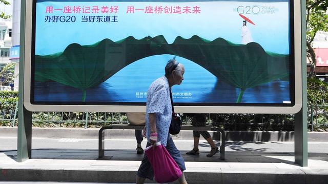 Eine Frau geht vor einem Plakat zum G20-Gipfel in Hangzhou vorbei.