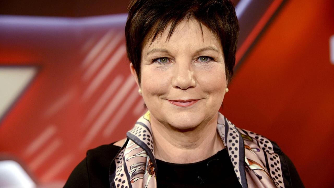 Ursula Weidenfels steht vor einem rotem Hintergrund im Fotostudio und schaut freundlich in die Kamera. Ursula Weidenfels steht vor einem rotem Hintergrund im Fotostudio und schaut freundlich in die Kamera.