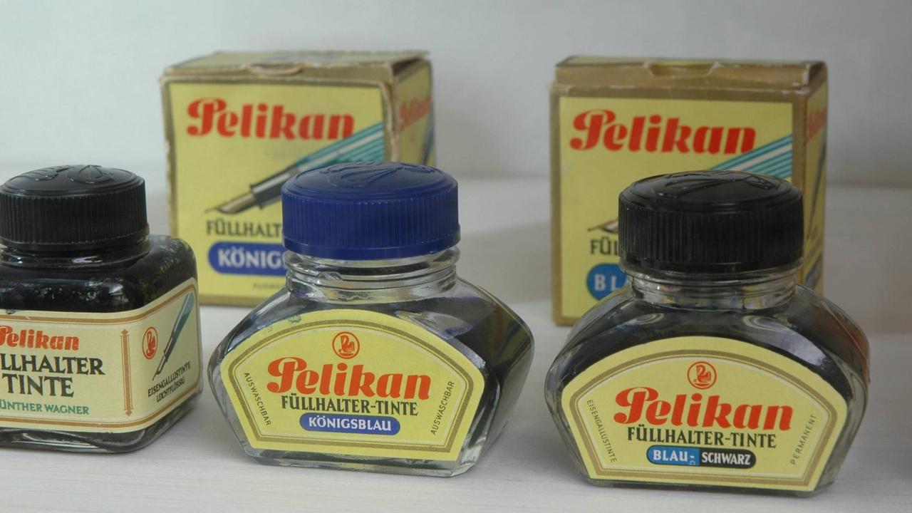 Alte Tintengläser der Marke Pelikan im Berliner Museum der Dinge mit gelben Etiketten und der Aufschrift "Füllhalter-Tinte".
