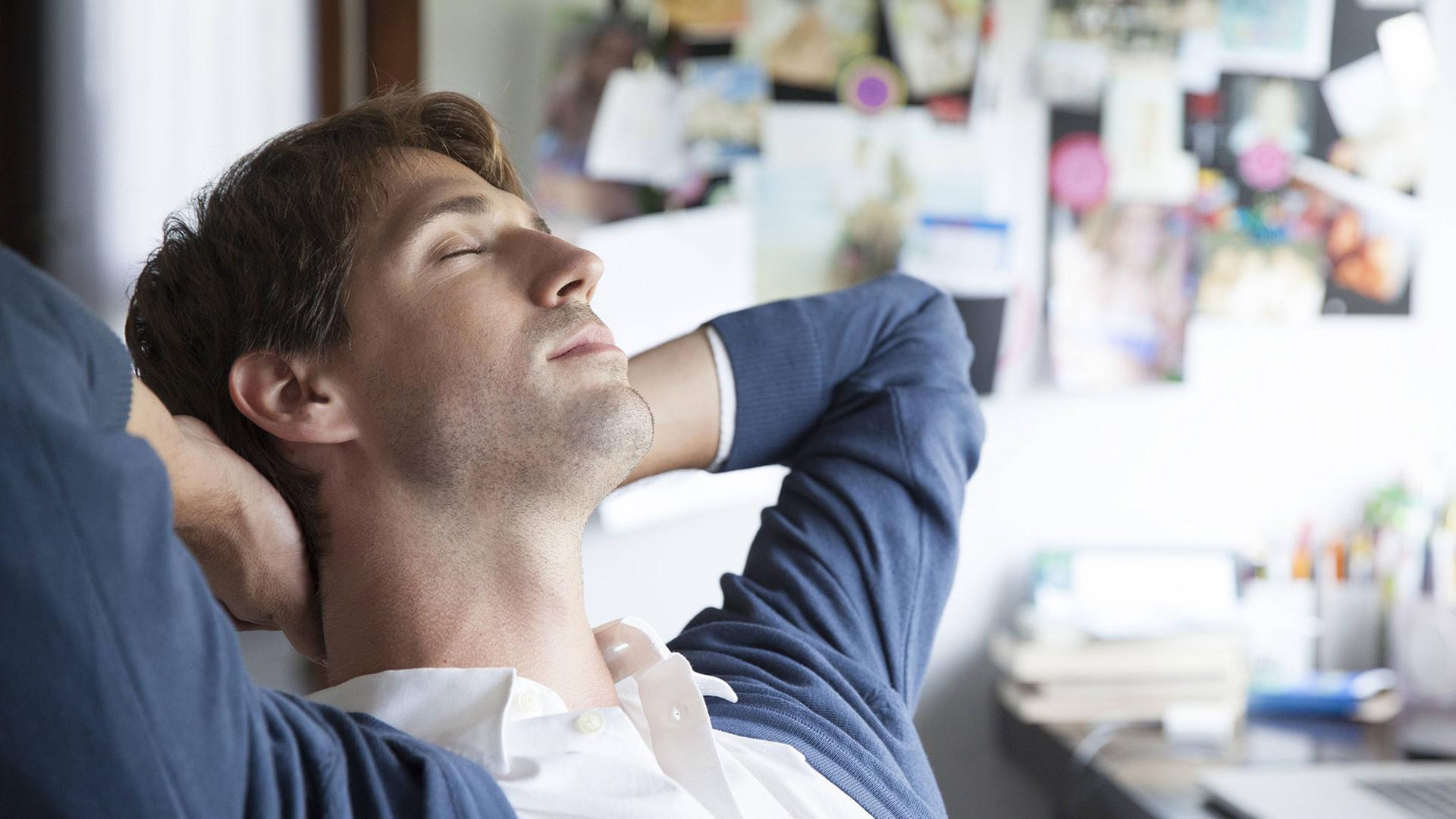 Ein Mann sitzt im Büro, hat die Augen geschlossen und träumt vor sich hin. Ein Mann sitzt im Büro, hat die Augen geschlossen und träumt vor sich hin.