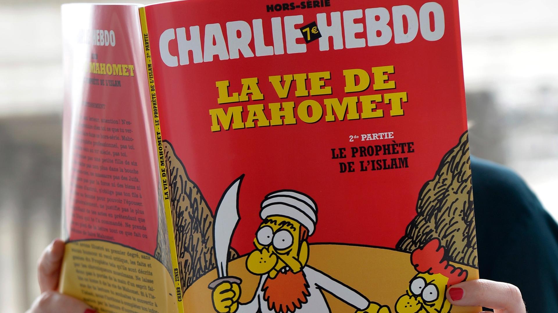 Eine nicht zu sehende Frau liest eine Ausgabe des französischen Satiremagazins Charlie Hebdo. Eine nicht zu sehende Frau liest eine Ausgabe des französischen Satiremagazins Charlie Hebdo.