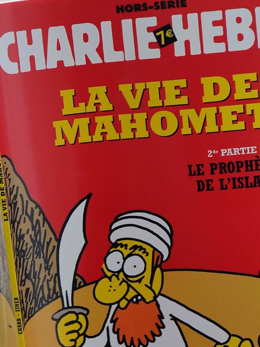 Eine nicht zu sehende Frau liest eine Ausgabe des französischen Satiremagazins Charlie Hebdo.
