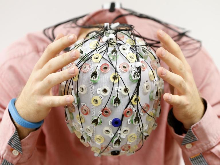 Ein Mann trägt eine EEG-Kappe