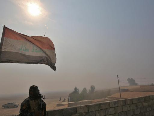 Ein irakischer Soldat steht unter einer Fahne in einem Dorf südlich der irakischen Stadt Mossul, die von der Terrormiliz IS befreit werden soll.