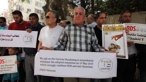 Palästinenser halten in Gaza Banner während eines Protestes gegen die Entscheidung des Deutschen Bundestages in Bezug auf den BDS hoch.