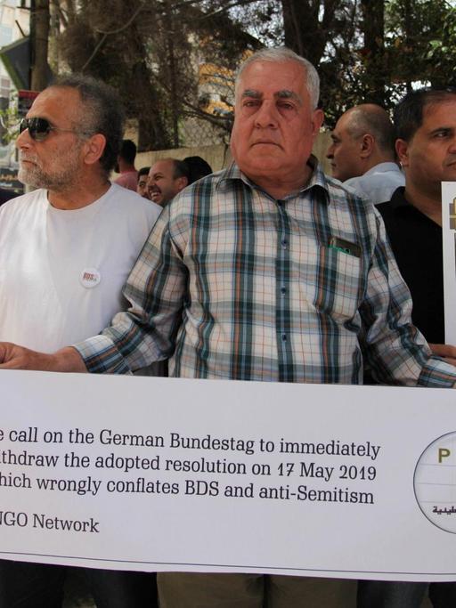 Palästinenser halten in Gaza Banner während eines Protestes gegen die Entscheidung des Deutschen Bundestages in Bezug auf den BDS hoch.