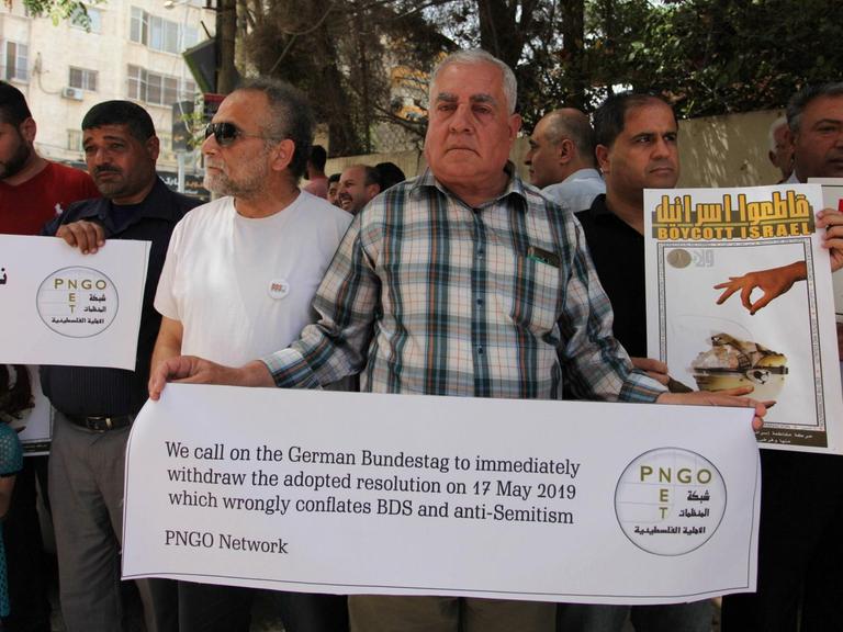 Palästinenser halten in Gaza Banner während eines Protestes gegen die Entscheidung des Deutschen Bundestages in Bezug auf den BDS hoch.