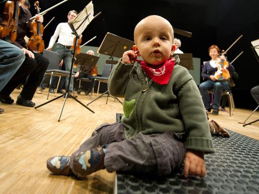 Der kleine Niklas fasst sich am 21.11.2012 in Heilbronn (Baden-Württemberg) vor Beginn des Babykonzerts des Württembergischen Kammerorchesters Heilbronn an sein Ohr. Eltern mit ihren Babys besuchten das ausverkaufte Konzert des Orchesters, das klassische Musik spielte.