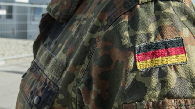 Ein Bundeswehrsoldat steht am 16.11.2015 im Wartezentrum Asyl in Erding (Bayern) vor Flüchtlingen. Im Wartezentrum für Migranten in Erding übernehmen Soldaten die Erstregistrierung von neu ankommenden Menschen und helfen bei Verpflegung und Unterkunft.