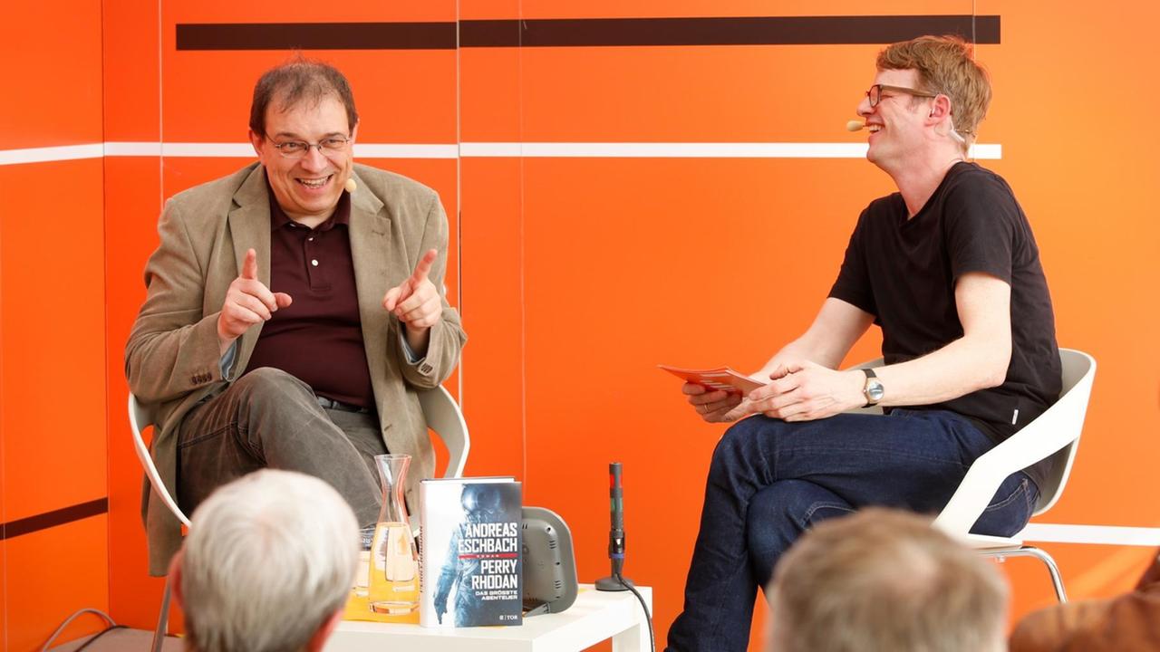 Andreas Eschbach (l.) lachend im Gespräch mit Moderator Kolja Mensing beim "Bücherfrühling" von Deutschlandfunk Kultur auf der Leipziger Buchmesse 2019