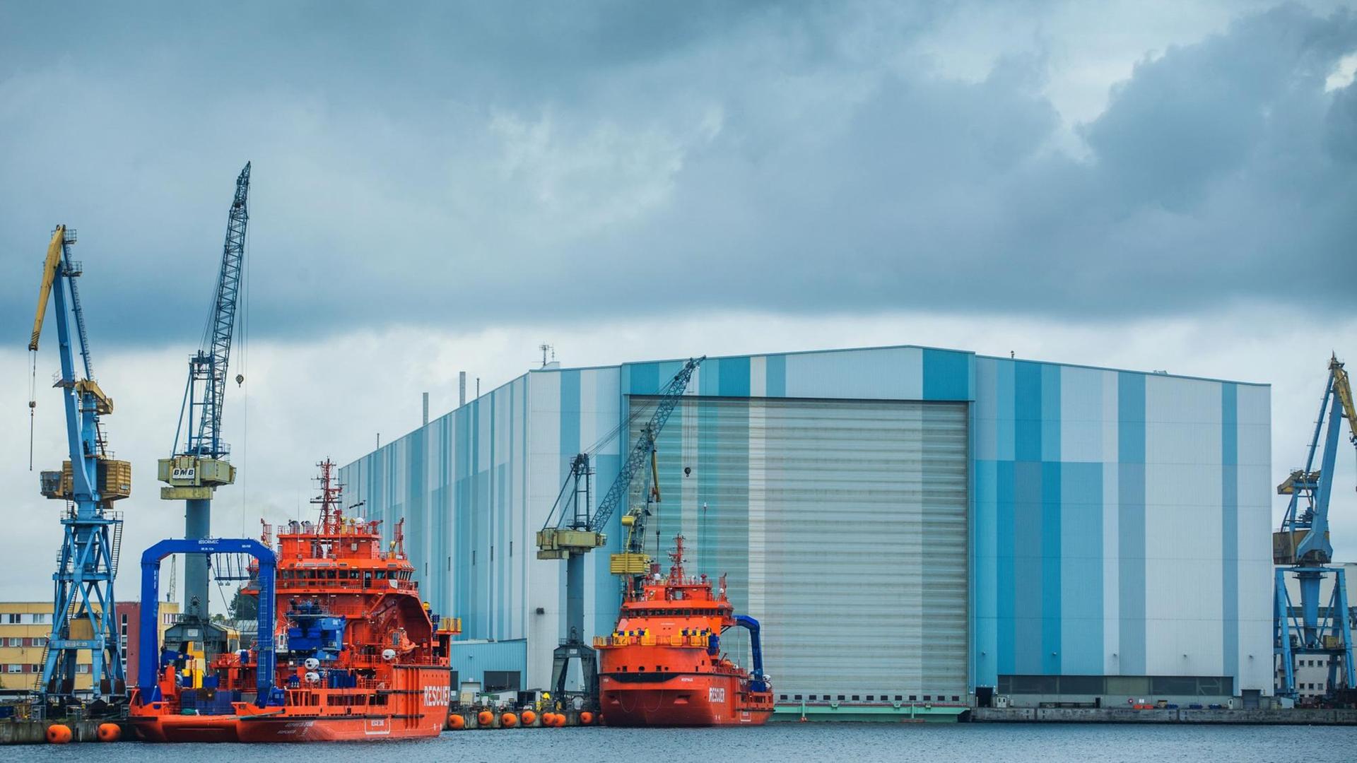 Dunkle Wolken ziehen am 09.06.2015 über die Schiffbauhalle der Nordic Yards Werft in Wismar (Mecklenburg-Vorpommern), vor der zwei eisbrechende Rettungs- und Bergungsschiffe in Ausrüstungskai liegen. Dunkle Wolken ziehen am 09.06.2015 über die Schiffbauhalle der Nordic Yards Werft in Wismar (Mecklenburg-Vorpommern), vor der zwei eisbrechende Rettungs- und Bergungsschiffe in Ausrüstungskai liegen.
