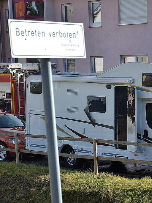 Ein Polizist steht am 04.11.2011 in Eisenach-Stregda vor einem qualmenden Wohnwagen, in dem zwei Leichen entdeckt wurden: die von Uwe Mundlos und Uwe Böhnhardt.