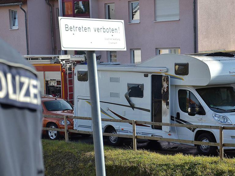 Ein Polizist steht am 04.11.2011 in Eisenach-Stregda vor einem qualmenden Wohnwagen, in dem zwei Leichen entdeckt wurden: die von Uwe Mundlos und Uwe Böhnhardt.