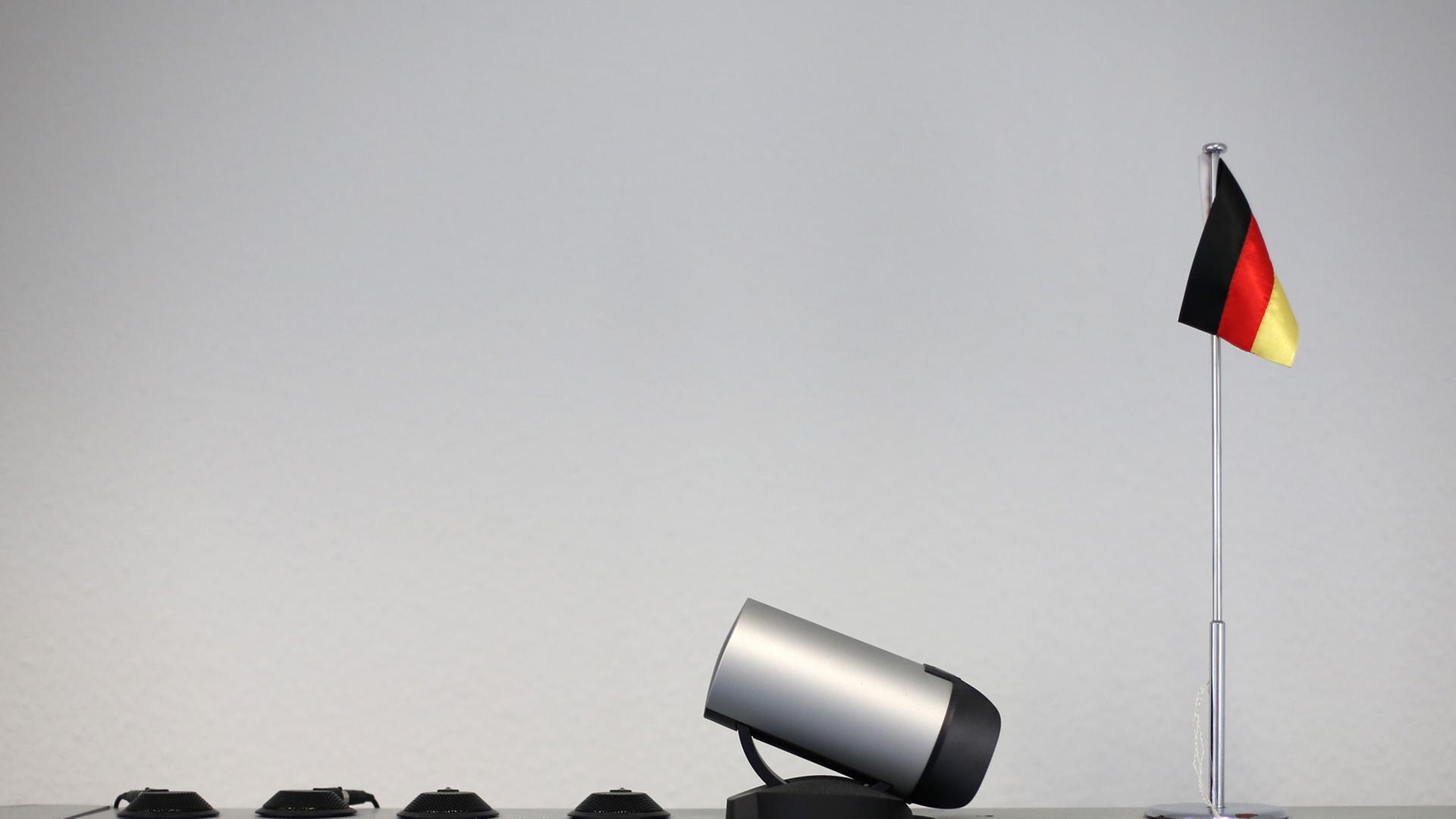 Eine kleine Deutschlandfahne steht am 17.05.2013 neben einer Kamera und Mikrofonen für eine Videokonferenz auf einem Monitor bei einer Pressekonferenz des Zollfahndungsamts in Hamburg.