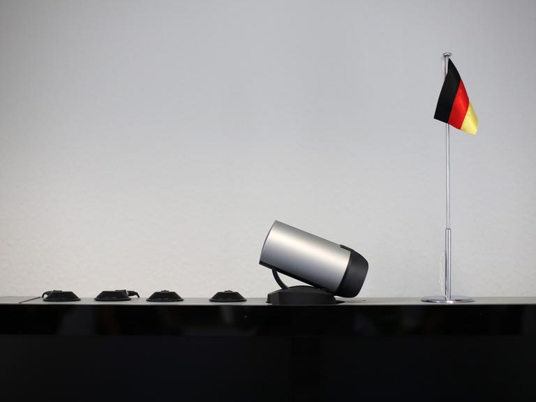 Eine kleine Deutschlandfahne steht am 17.05.2013 neben einer Kamera und Mikrofonen für eine Videokonferenz auf einem Monitor bei einer Pressekonferenz des Zollfahndungsamts in Hamburg.