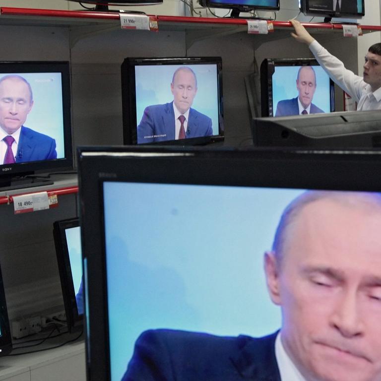 Wladimir Putin ist in einem Geschäft auf diversen TV-Bildschirmen zu sehen.