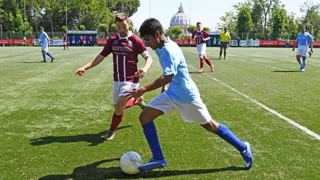 Ein Spieler des Teams Mater Ecclesiae aus Vatikanstadt kontrolliert den Ball beim Clericus Cup 2016 i n Rom. Im Hintergrund ist der Petersdom zu sehen.