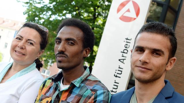 Hasma Olabi (l-r) aus Afghanistan, Nebai Kahsai Hable aus Eritrea und Abduk Samad Najm aus Syrien sitzen am 04.08.2015 vor einem Schild der Arbeitsagentur für Arbeit in Hannover (Niedersachsen).