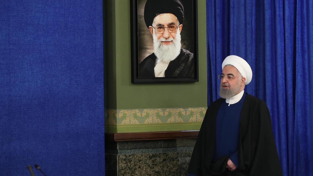 Hassan Rouhani läuft an einem Porträt von Ajatollah Chamenei vorbei. Hassan Rouhani läuft an einem Porträt von Ajatollah Chamenei vorbei.