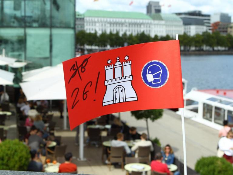 Eine Pappflagge mit dem Hamburg-Wappen sowie der Aufschrift 2G steckt in einer Mauer in der Hamburger Innenstadt vor einem Restaurant an der Alster.