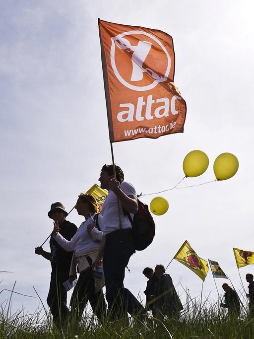 Demonstranten mit Fahnen ziehen am Straßenrand entlang.