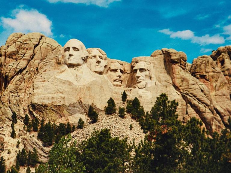 Ansicht des Mount Rushmore mit den vier in einen Felsen gehauenen Präsidentenköpfen.