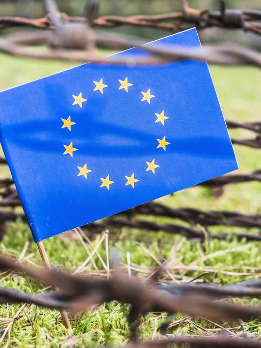 Flagge der EU hinter Stacheldrahtzaun