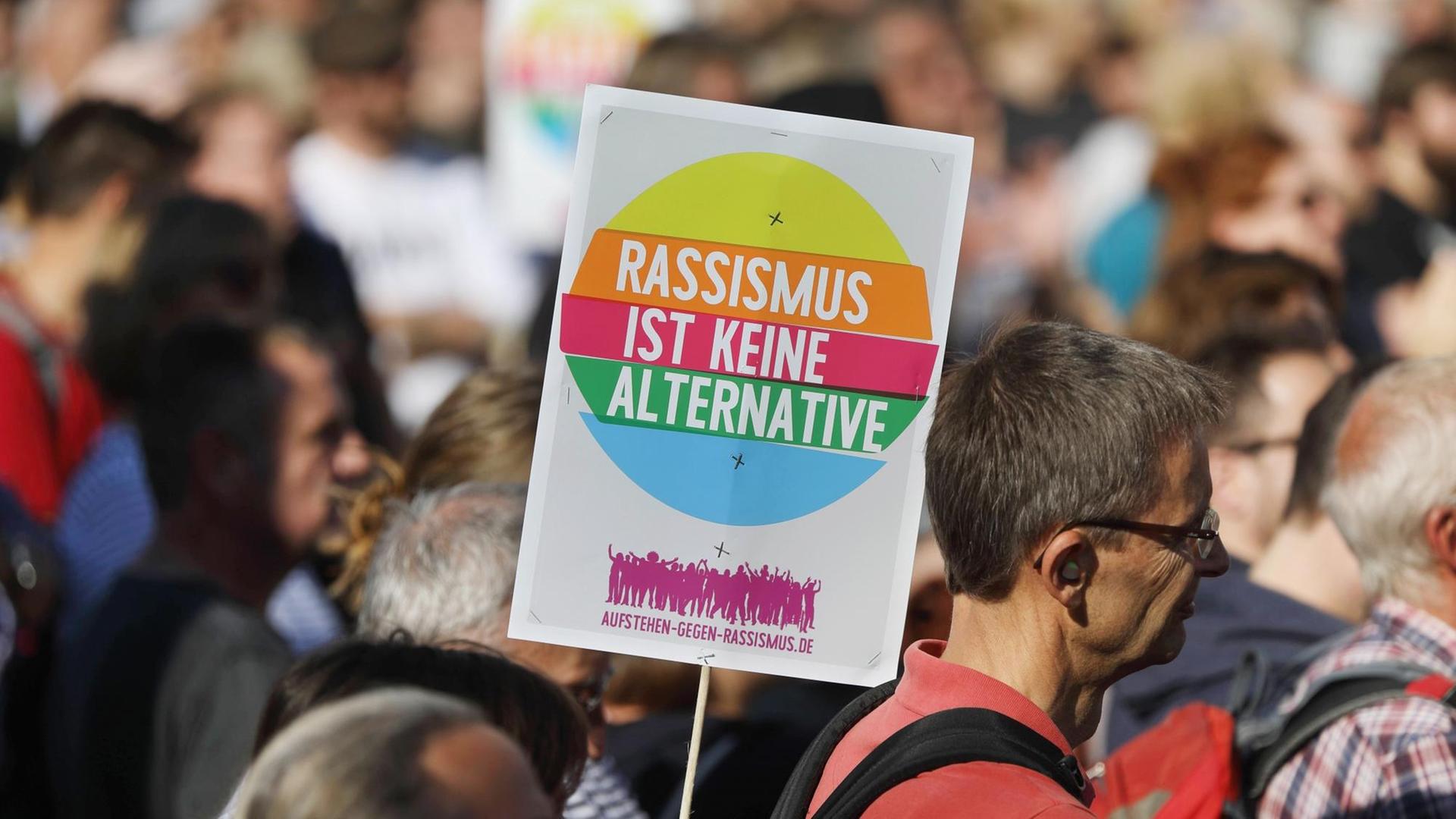 Ein Schild mit der Aufschrift " Rassismus ist keine Alternative" inmitten der Menschenmenge auf der Großkundgebung Ulteilbar in Berlin. Ein Schild mit der Aufschrift " Rassismus ist keine Alternative" inmitten der Menschenmenge auf der Großkundgebung Ulteilbar in Berlin.