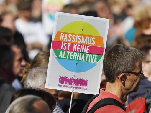 Ein Schild mit der Aufschrift " Rassismus ist keine Alternative" inmitten der Menschenmenge auf der Großkundgebung Ulteilbar in Berlin.
