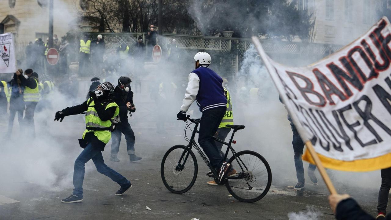Demonstranten in Paris stehen in einer Wolke von Tränengas, das von Polizisten während eines "Gelbwesten"-Protests eingesetzt wurde. Demonstranten in Paris stehen in einer Wolke von Tränengas, das von Polizisten während eines "Gelbwesten"-Protests eingesetzt wurde.