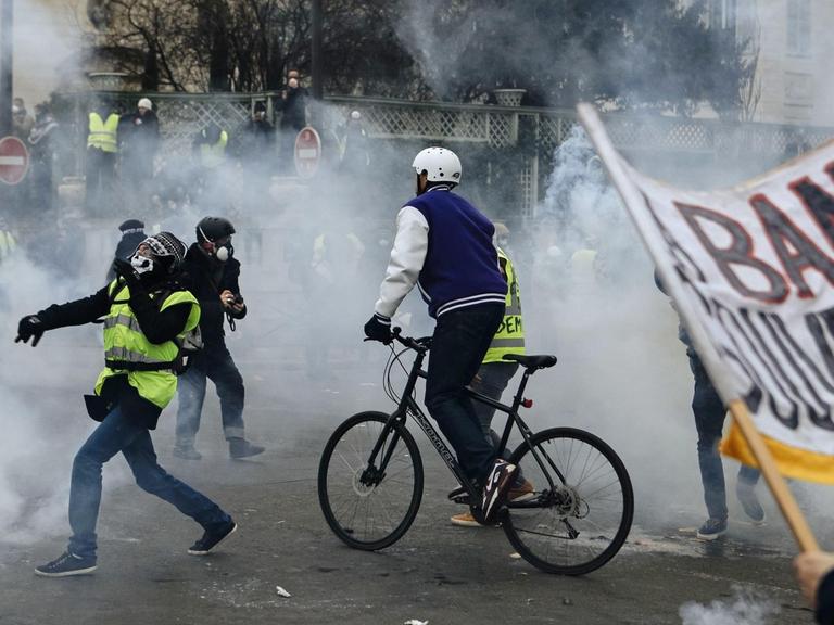 Demonstranten in Paris stehen in einer Wolke von Tränengas, das von Polizisten während eines "Gelbwesten"-Protests eingesetzt wurde.
