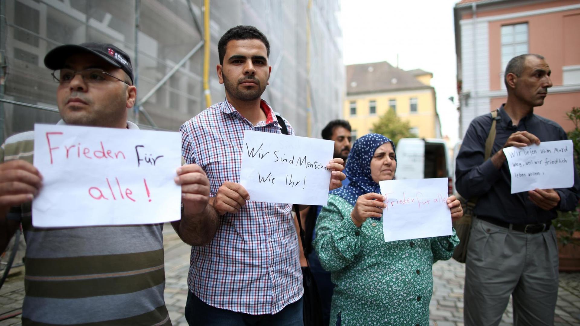 Flüchtlinge aus Syrien und dem Irak halten in Ansbach nach dem Anschlag Schilder hoch, mit denen sie für Frieden demonstrieren.