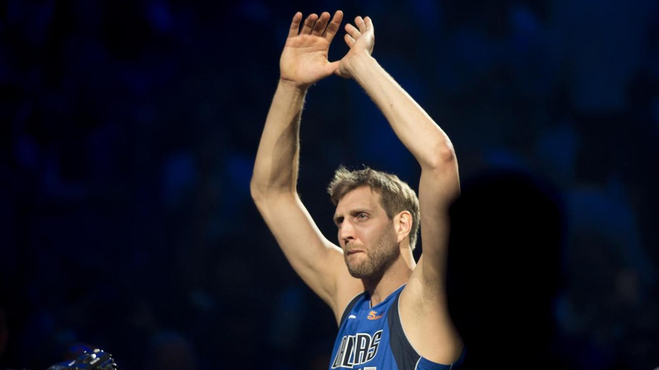 Dirk Nowitzki bei seinem Abschiedsspiel: Er trägt ein blaues Dallas-Trikot und winkt mit gerührter Mine in die Menge. Dirk Nowitzki bei seinem Abschiedsspiel: Er trägt ein blaues Dallas-Trikot und winkt mit gerührter Mine in die Menge.
