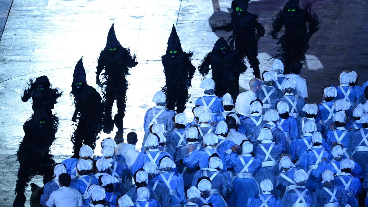 Aus der Show zur Olymipa-Eröffnung 2012, inszeniert vom Filmemacher Danny Boyle: Krankenschwester und Ärzte trotzen einem Ansturm finster aussehender Gestalten Aus der Show zur Olymipa-Eröffnung 2012, inszeniert vom Filmemacher Danny Boyle: Krankenschwester und Ärzte trotzen einem Ansturm finster aussehender Gestalten