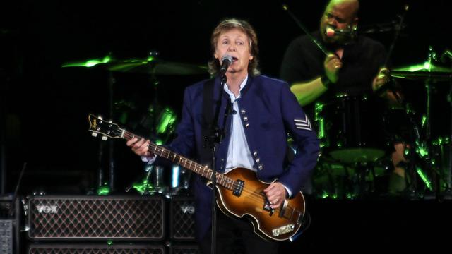 Paul McCartney steht bei einem Konzert in Salvador in Brasilien 2017 mit einer Gitarre auf der Bühne vor einem Mikrofon.