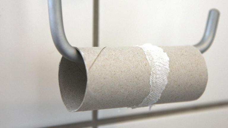 Aufgebrauchte Toilettenpapierrolle auf einem Halter in einem Badezimmer. Aufgebrauchte Toilettenpapierrolle auf einem Halter in einem Badezimmer.