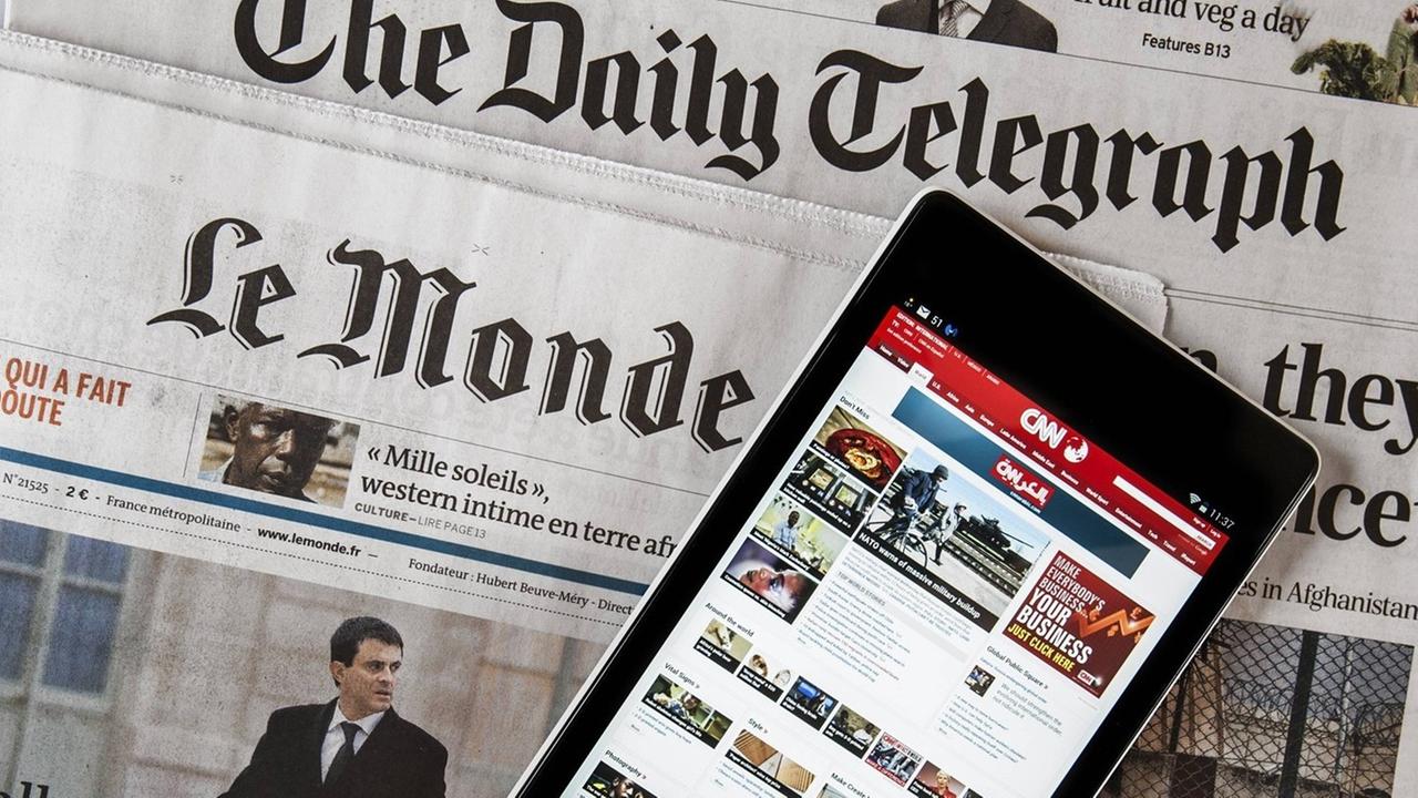Das Touchscreen eines digitalen Tablets zeigt die CNN International online Nachrichten, welches auf den beiden Zeitungen, der britische "The daily Telegraph" und der französischen "Le monde" liegt. Das Touchscreen eines digitalen Tablets zeigt die CNN International online Nachrichten, welches auf den beiden Zeitungen, der britische "The daily Telegraph" und der französischen "Le monde" liegt.