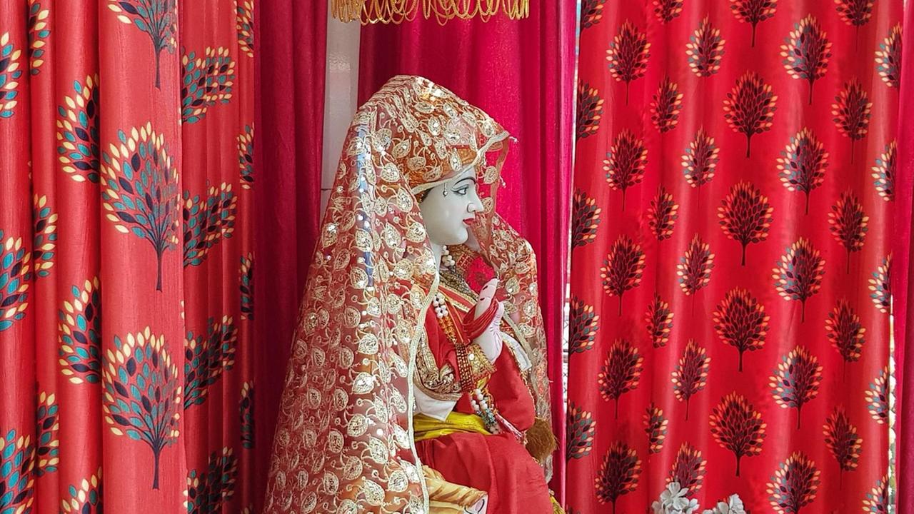 Eine Statue in traditionellem Gewand steht für Gläubige und Besucher in einem Tempel. Eine Statue in traditionellem Gewand steht für Gläubige und Besucher in einem Tempel.