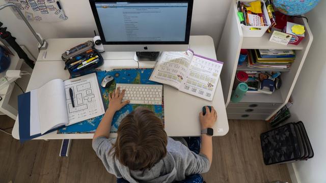 Ein Junge sitzt an seinem Schreibtisch vor dem Computer.