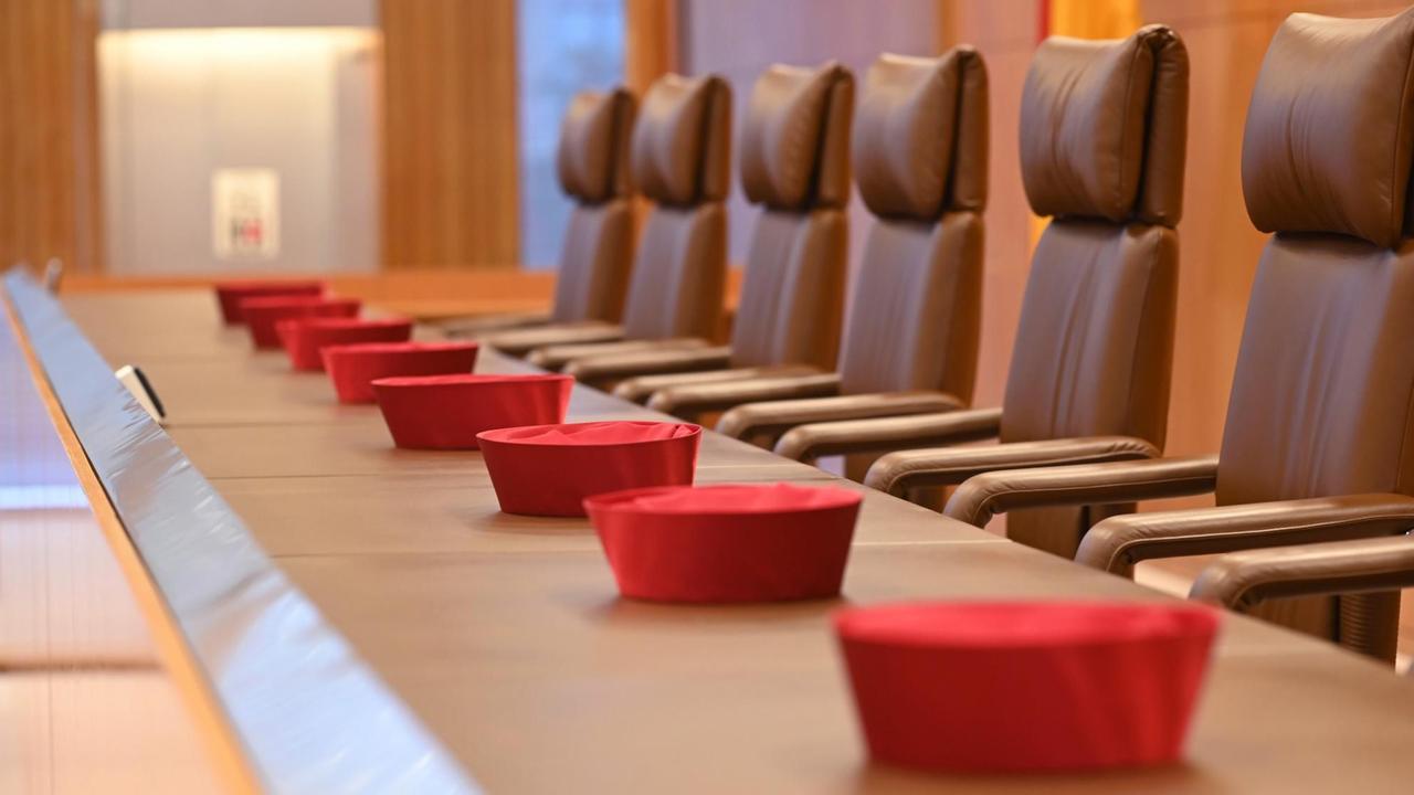 Auf der Richterbank im Sitzungssaal im Bundesverfassungsgericht liegen die roten Barette der Bundesverfassungsrichter des ersten Senats. Auf der Richterbank im Sitzungssaal im Bundesverfassungsgericht liegen die roten Barette der Bundesverfassungsrichter des ersten Senats.