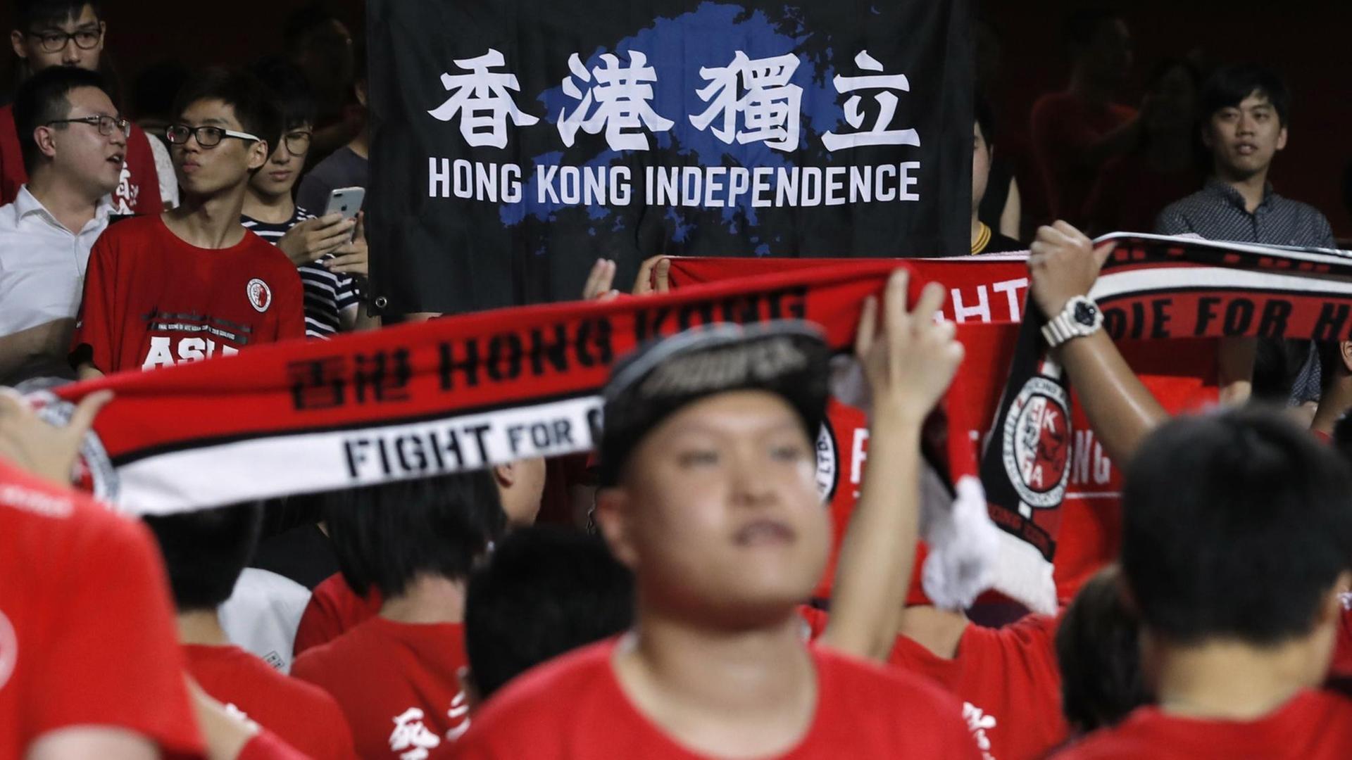Einige Fans der Fußballnationalmannschaft von Hongkong halten einen Banner mit der Aufschrift "Hong Kong Unabhängigkeit" hoch. Einige Fans der Fußballnationalmannschaft von Hongkong halten einen Banner mit der Aufschrift "Hong Kong Unabhängigkeit" hoch.