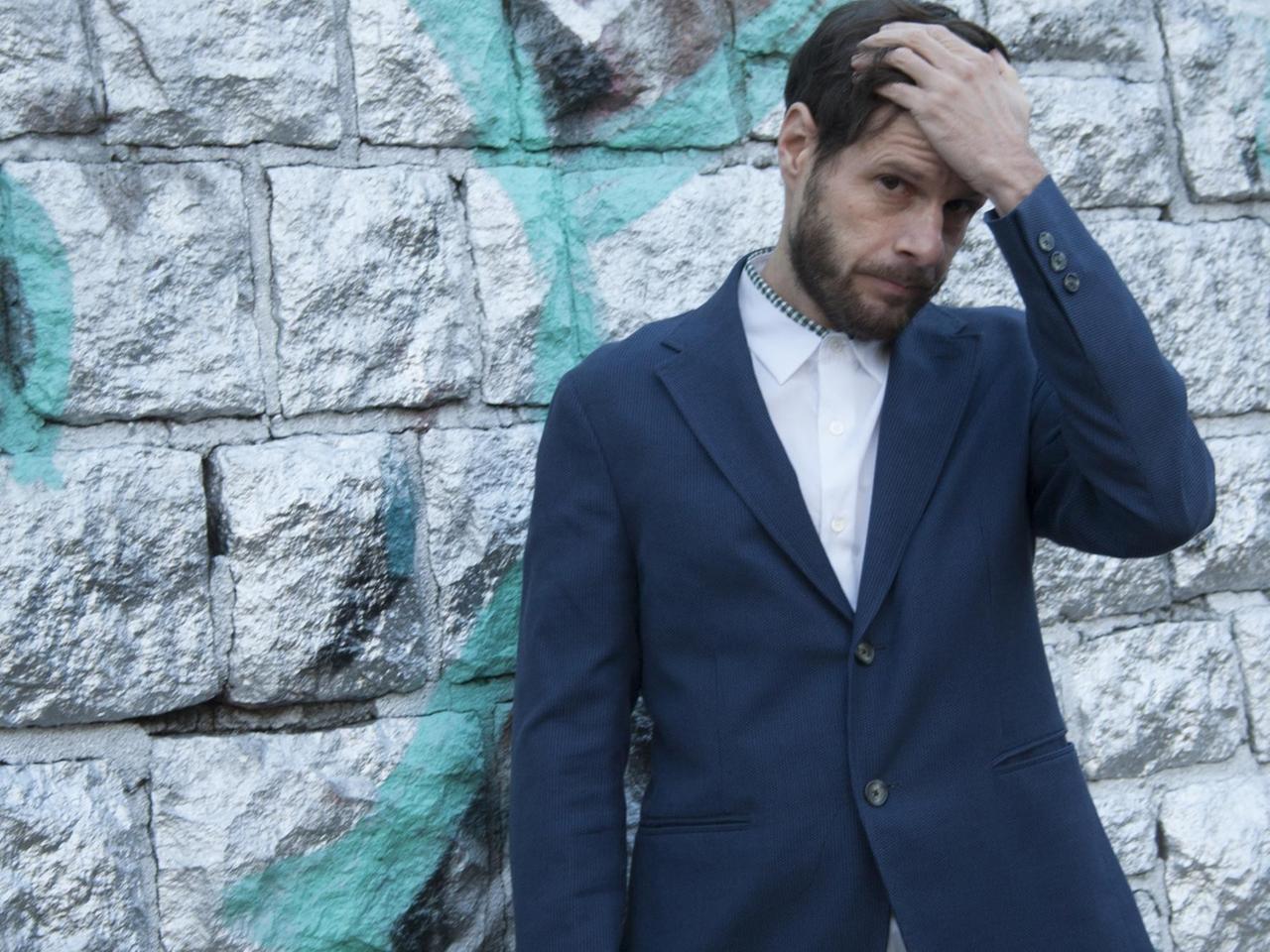 Der Feature-Autor Christian Lerch steht vor einer Wand und fasst sich in die Haare. Der Feature-Autor Christian Lerch steht vor einer Wand und fasst sich in die Haare.