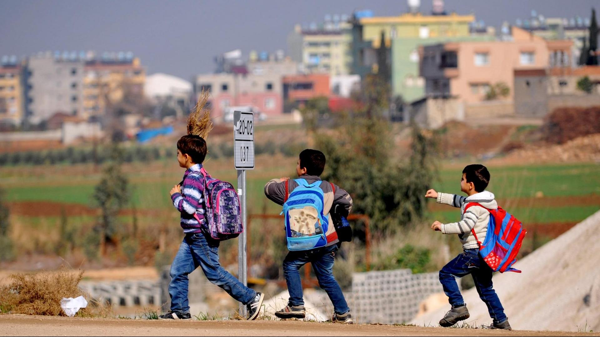 Man sieht drei syrische Flüchtlingskinder mit Schulranzen. Man sieht drei syrische Flüchtlingskinder mit Schulranzen.