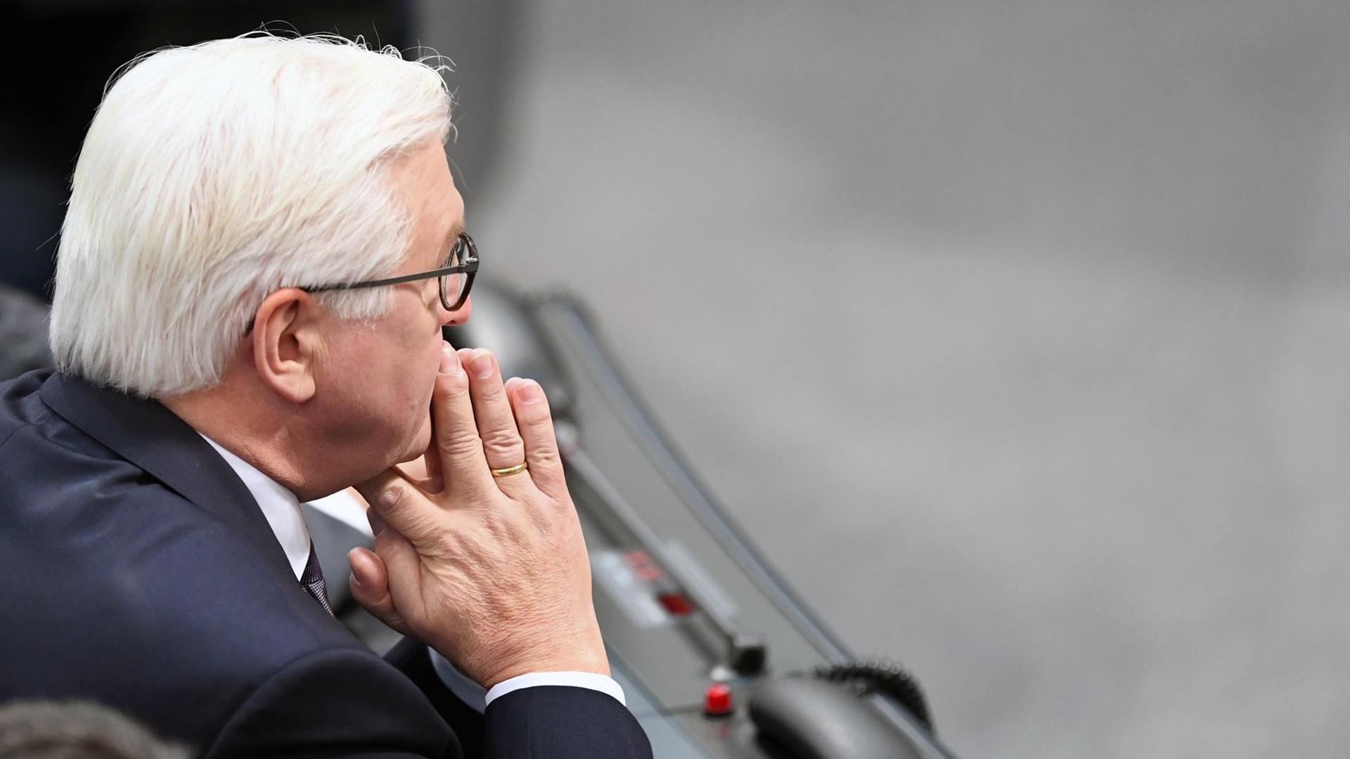 Der Bundespräsident Frank-Walter Steinmeier sitzt im Bundestag mit ineinander verschlungene Händen vor dem Gesicht.