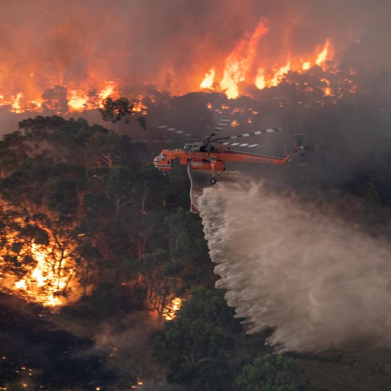 Blick auf einen  Helikopter, der Waldbrände aus der Luft löscht