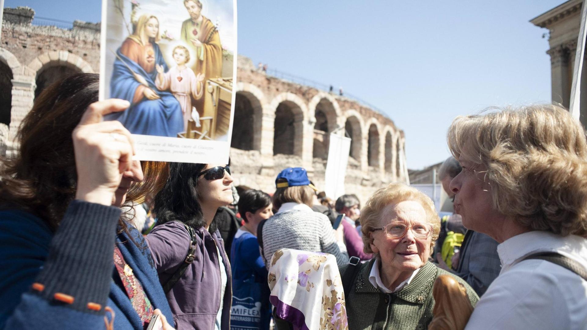 Versammlungsteilnehmer vor der Arena in Verona, Plakat mit Joseph, Maria und dem Jesuskind im Vordergrund