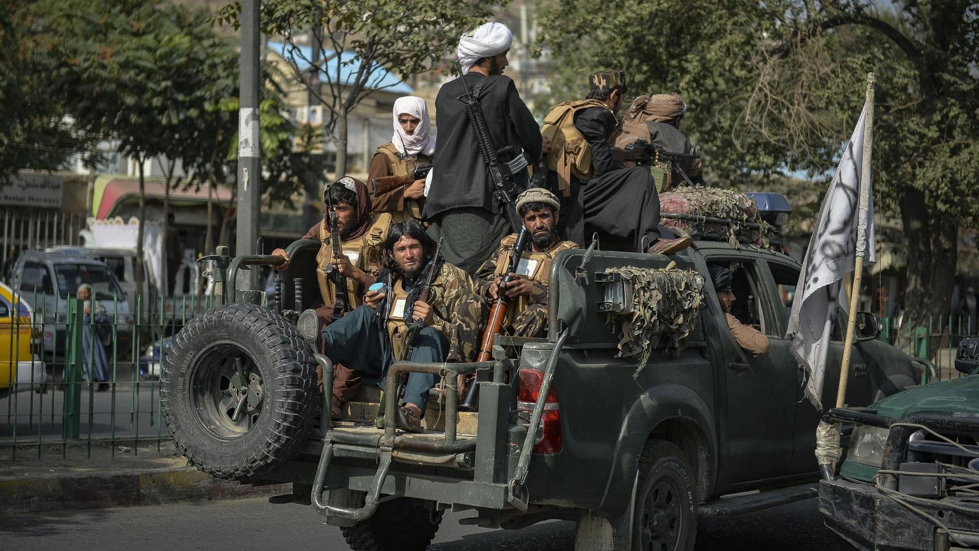 Taliban-Kämpfer patrouillieren in einem Auto entlang einer Straße.