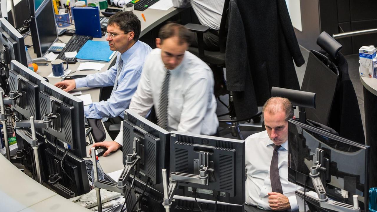 Ausschnitt eines runden Schreibtisches auf dem Parkett der Frankfurter Börse: Vier Händler starren auf Computerbildschirme, jeder hat vier an seinem Arbeitsplatz. Ausschnitt eines runden Schreibtisches auf dem Parkett der Frankfurter Börse: Vier Händler starren auf Computerbildschirme, jeder hat vier an seinem Arbeitsplatz.