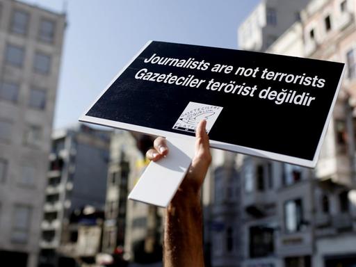 Ein Demonstrant reckt ein Plakat mit der Aufschrift "Journalisten sind keine Terroristen" in die Höhe.